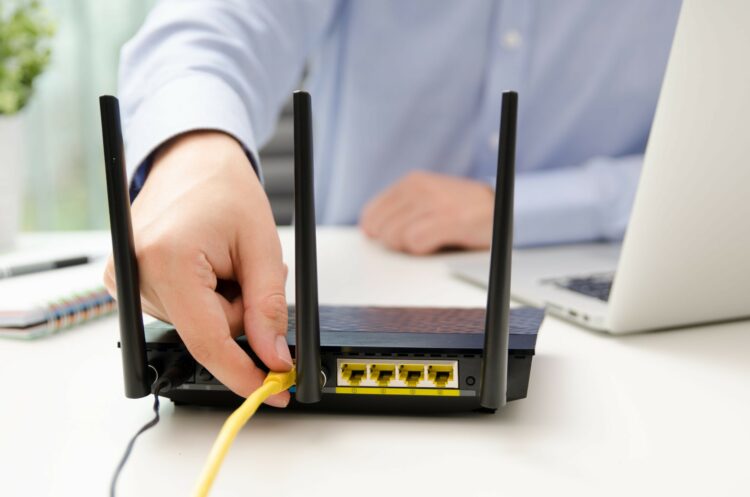 Man,Plugs,Ethernet,Cable,Into,Router.,Router,Wireless,Wire,Broadband