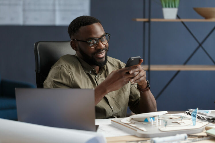 Young,Afro-american,Man,Using,Smartphone,And,Smiling.,Happy,Businessman,Using