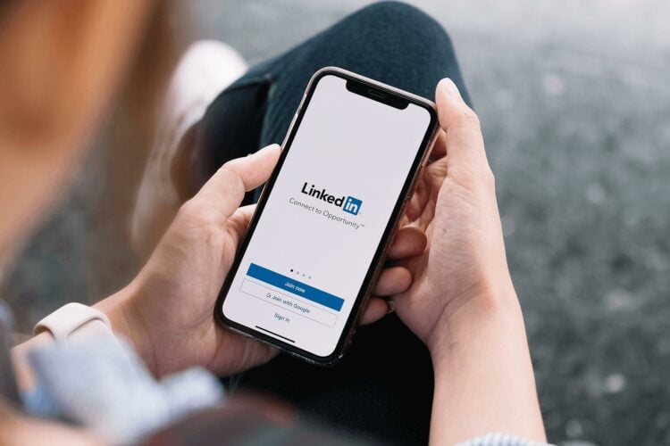 Connect Us - Person using LinkedIn on mobile phone